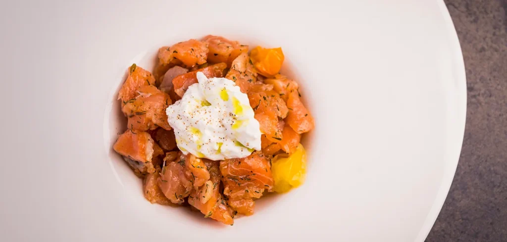 Tartar de salmón ahumado con tomates confitados, burrata y aceite de albahaca