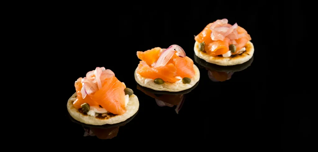 Mini pizza fina de salmón ahumado, mozzarella, cebolla roja y alcaparras